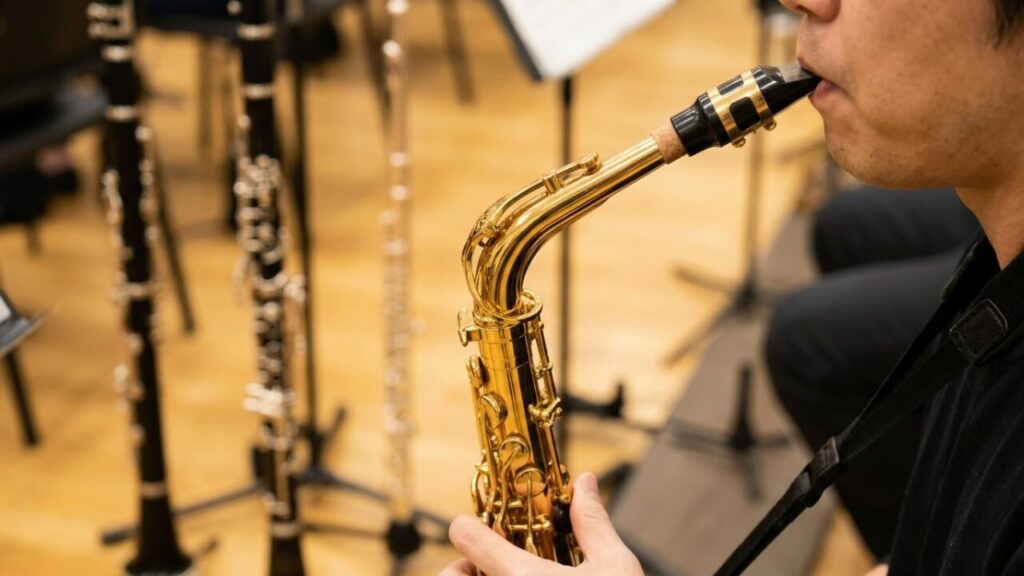 サックスのマウスピースとリードを調整する日本人奏者の手元。金属製の本体だが、木管楽器に分類される理由であるシングルリードの発音機構を強調。